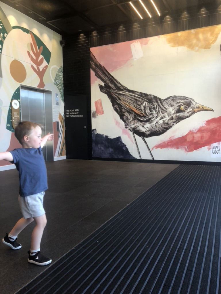 A photo of Louis dancing in front of a mural of a bird