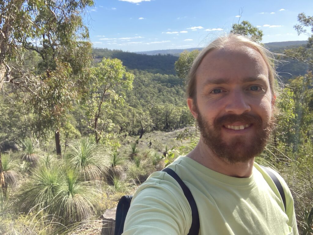 Photo: selfie of me with a big valley and thousands of trees in the background. 