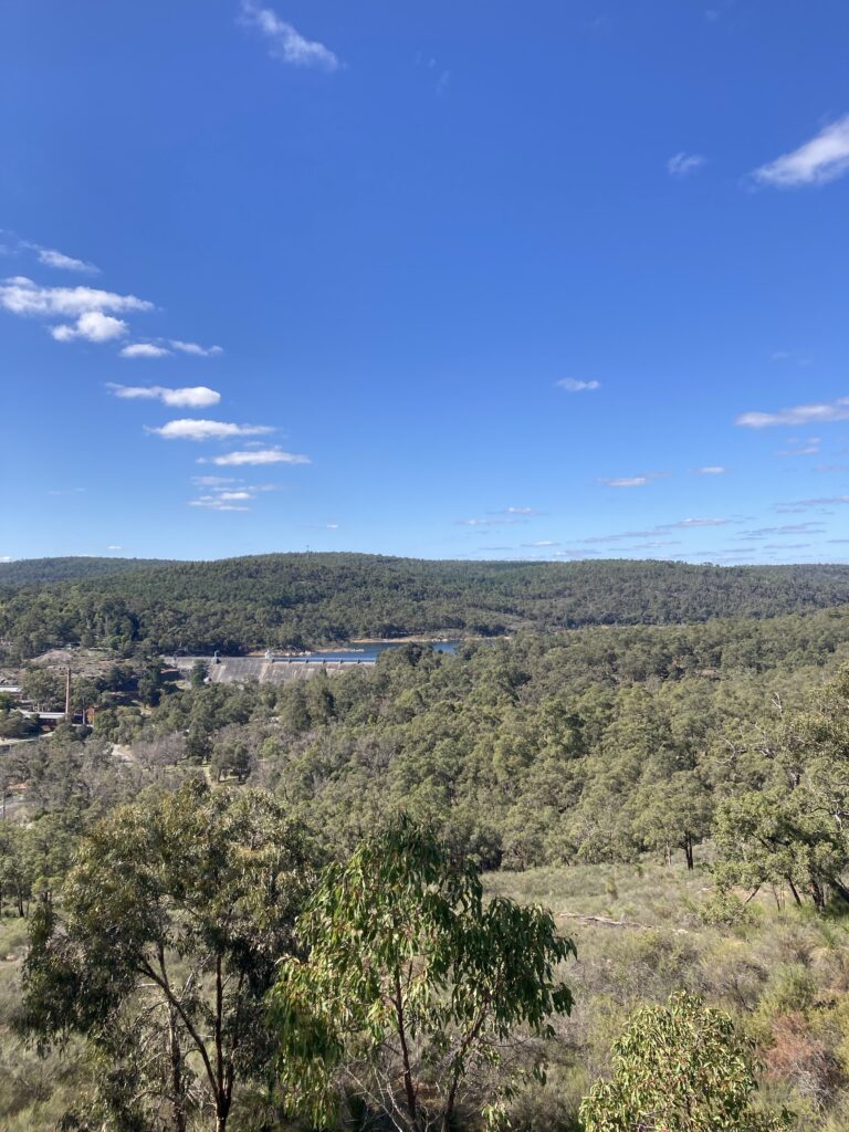 Photo: a wide photo of the bush landscape and the blue skies. You can see the Mundaring Weir (a giant dam) in the distance. It looks smaller in the photo than it did in real life.